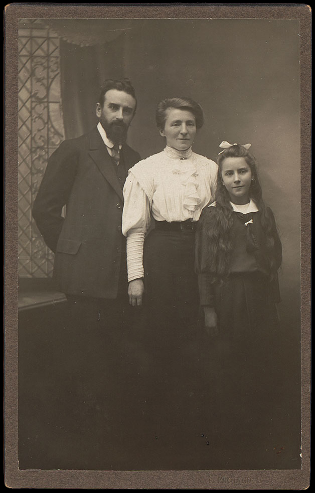 Family portrait of Paul, Ida and Alice Golay. All three are stood up, Paul is wearing a suit, Ida a white blouse, and Alice a dark-coloured dress with a white collar.