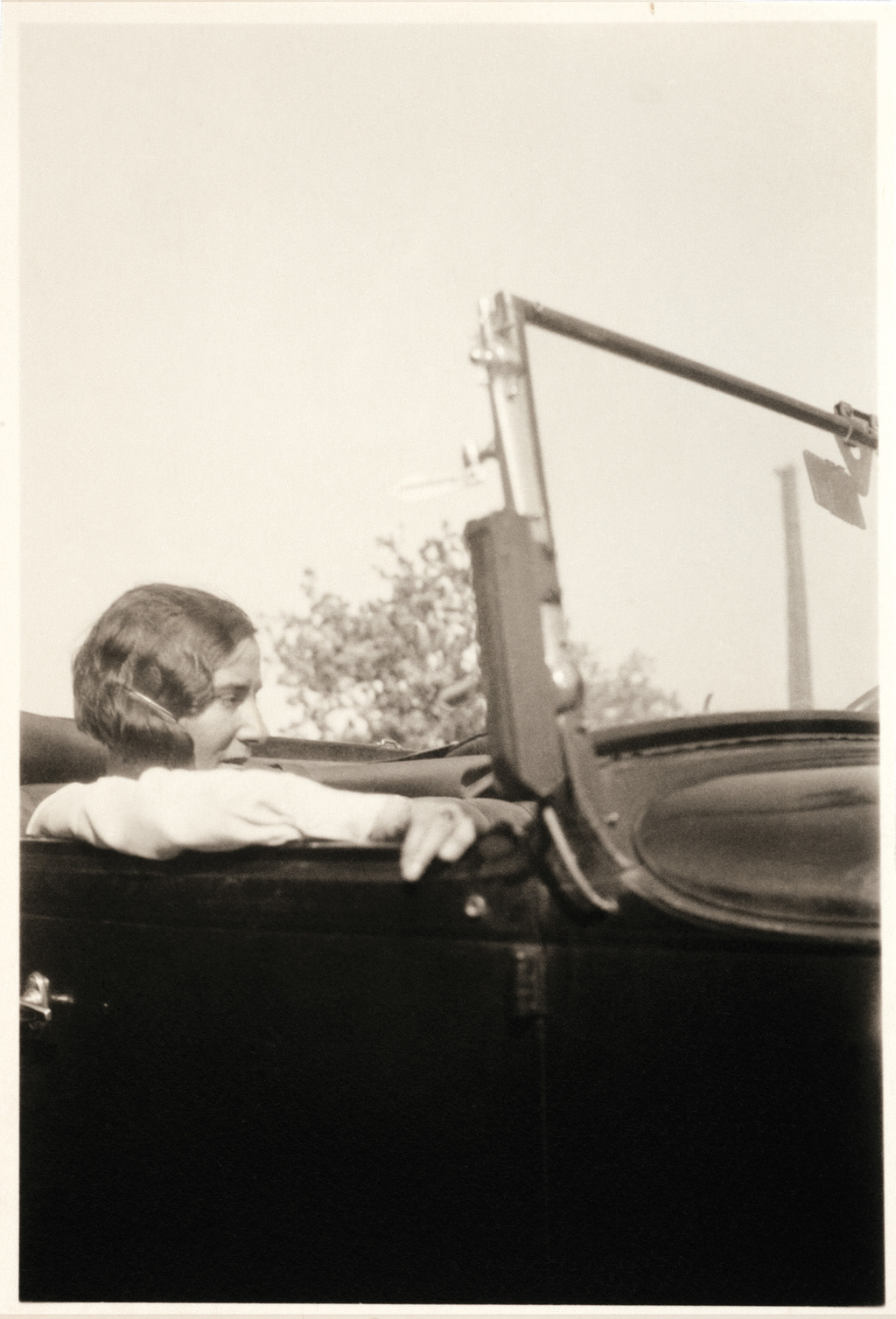 Black and white photo of Alice Rivaz in the passenger seat of a cabriolet.
